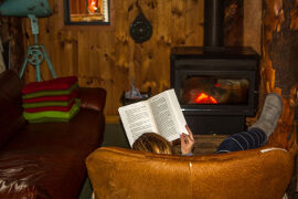 reading a book by the fire at Bruny Island Lodge
